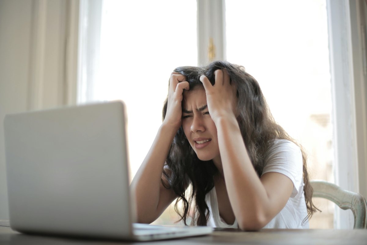 Ragazza con le mani fra i capelli di fronte a un computer